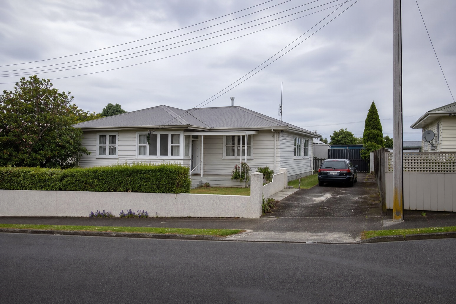 Frankton villa garden with weatherboard verandah, mature camellia hedge along the front, autumn morning light